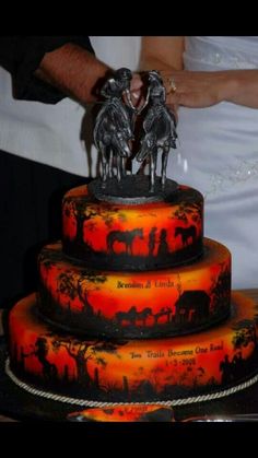 a wedding cake decorated with elephants and people on the top is red, orange and black