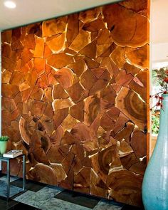 a large wooden wall next to a vase on a black tile floor in a room