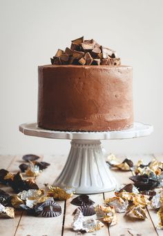 a chocolate cake sitting on top of a white cake platter covered in gold foil