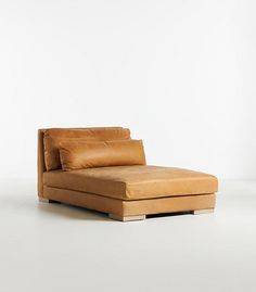 a tan leather chaise lounge chair with pillows