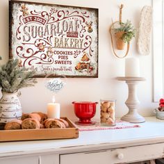 a white table topped with lots of food next to a wall mounted sign that says sugarflake bakery