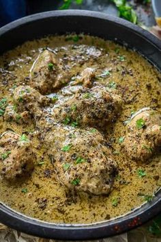 some meatballs are in a pan with gravy on the side and garnished with parsley