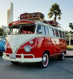 a red and white vw bus parked in a parking lot with luggage on top