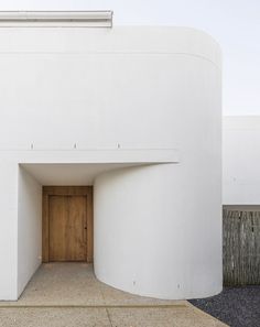 an entrance to a white building with a wooden door on the outside and side walls