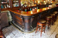 an old fashioned bar with stools and bottles on it