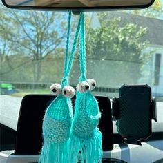 there are two tassels hanging from the dashboard of a car with eyes on them