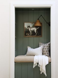 a dog is sitting on a bench in the corner of a room with green paneling