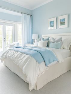 a bedroom with light blue walls and white bedding