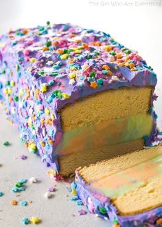 a cake with purple frosting and sprinkles on it's side