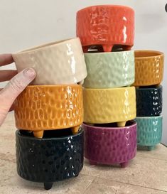 a hand is holding a stack of ceramic bowls