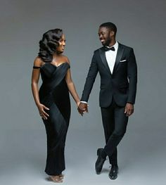 a man in a tuxedo and a woman in a black dress holding hands