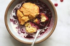 a close up of a bowl of food with berries and crumbs on it