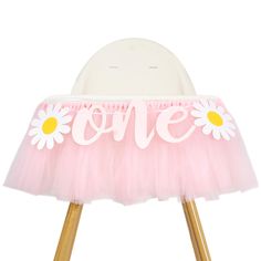 a pink and white chair with the word love spelled on it's back, sitting on wooden legs