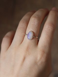 This dainty and extremely delicate ring features a beautiful Australian Lightning Ridge opal, set in a fine silver bezel with open back. The band is made with a sterling silver square wire. Size 6Handmade It's a perfect everyday ring - simple, yet full of character. Can be stacked and combined with other rings or worn by itself, for a more minimalist look. Delicate purples make each opal absolutely unique, with its own stunning colours and inclusions. The look of the gemstone changes in differen Classic Opal Moonstone Ring As Gift, Minimalist Opal Stackable Promise Rings, Adjustable Minimalist Moonstone Ring In Sterling Silver, Minimalist Adjustable Sterling Silver Moonstone Ring, Minimalist Everyday Jewelry With Cabochon, Minimalist Everyday Cabochon Jewelry, Delicate Sterling Silver Opal Ring, Delicate Opal Gemstone Rings, Minimalist Opal Birthstone Ring