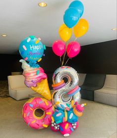 an ice cream cone, donut, and balloon birthday decoration in the shape of numbers