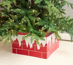 a small christmas tree in a red brick planter with lights on it's branches