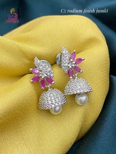 Super cute and super low price, rhodium tone silver Jhumka studded with American diamond crystals and in floral design studded with CZ color stones. Diwali American Diamond Jhumkas, Bollywood Style Cubic Zirconia Jhumkas, Silver Jhumkas With Stone Work For Diwali, Silver Jhumkas With Stone Work, Silver Jhumkas With Stone Work For Gift, Silver Chandbali American Diamond Jhumkas, Silver Bollywood Jhumkas With American Diamonds, Silver Bridal Earrings With Latkans In American Diamond, Silver Cubic Zirconia Jhumkas For Wedding