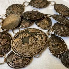 a bunch of antique coin necklaces on a white tablecloth with some old coins