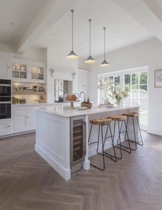 an open kitchen with white cabinets and counter tops is pictured in this image, there are four stools at the center of the island