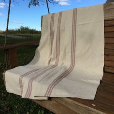 a white and red blanket sitting on top of a wooden bench