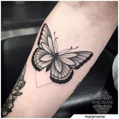 a black and white butterfly tattoo on the arm