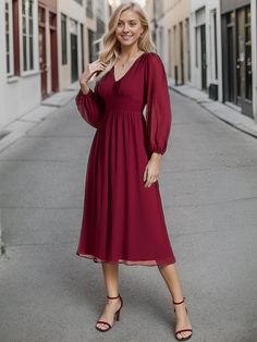 a woman in a red dress is standing on the street and smiling at the camera