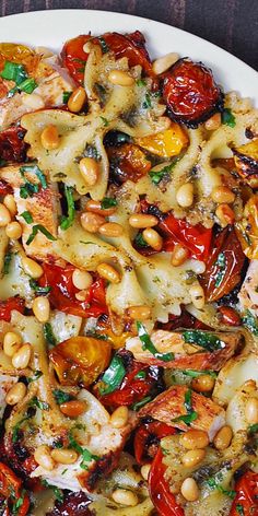 a white plate topped with pasta and veggies on top of a wooden table