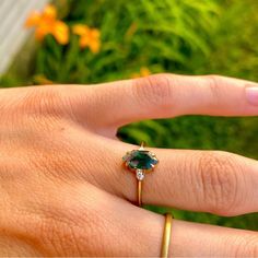 a woman's hand with a ring on it and an emerald stone in the middle