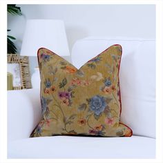 a yellow floral pillow sitting on top of a white couch