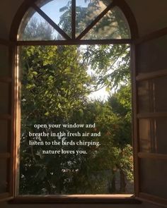 an open window with a quote written on the outside and trees in the back ground