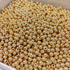 some gold beads are in a white box