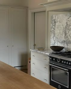 a kitchen with an oven, counter top and cupboards in the backround