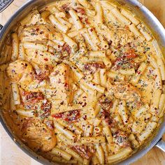 a pan filled with pasta and sauce on top of a wooden table