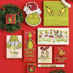 the grinch christmas card collection is displayed on a red wall with wreath and decorations