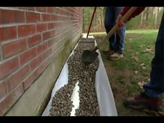 a man is shoveling gravel into a hole in the side of a brick wall