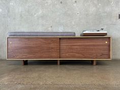 the sideboard is made out of wood and has a gray cushion on one end