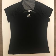 the adidas shirt is black and has silver detailing on it's collarline