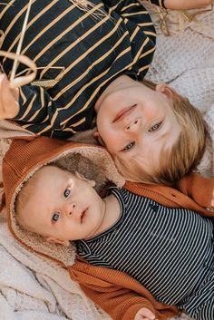 two little boys laying on top of each other in the middle of an outdoor area