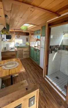 the inside of a tiny home with wood floors and green cabinetry on the walls