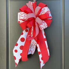 a red and white polka dot bow hanging on the front door to give it a festive touch