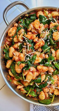 a pan filled with pasta and spinach covered in parmesan cheese