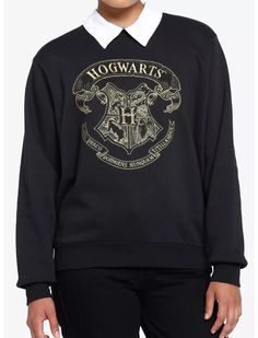 a woman wearing a harry potter sweater with hogwart's crest on the front