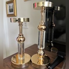 two metal candlesticks sitting on top of a wooden table next to a mirror