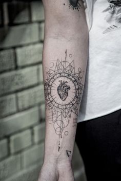 a person with a tattoo on their arm that has a heart and compass in it