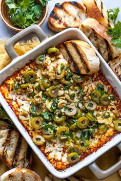 a casserole dish filled with vegetables and bread on a table next to other foods