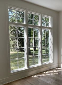 an empty room with large windows and wood flooring on the side of the wall