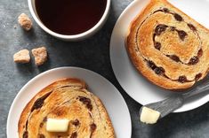 two white plates topped with pastries next to a cup of coffee and sugar cubes