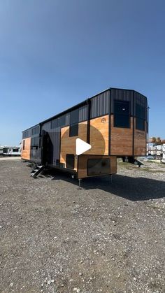 a black and brown trailer parked on top of a gravel field next to a building