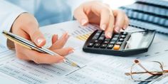 two people working at a desk with calculator, glasses and pen on it