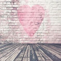 an empty wooden floor in front of a brick wall with a heart painted on it